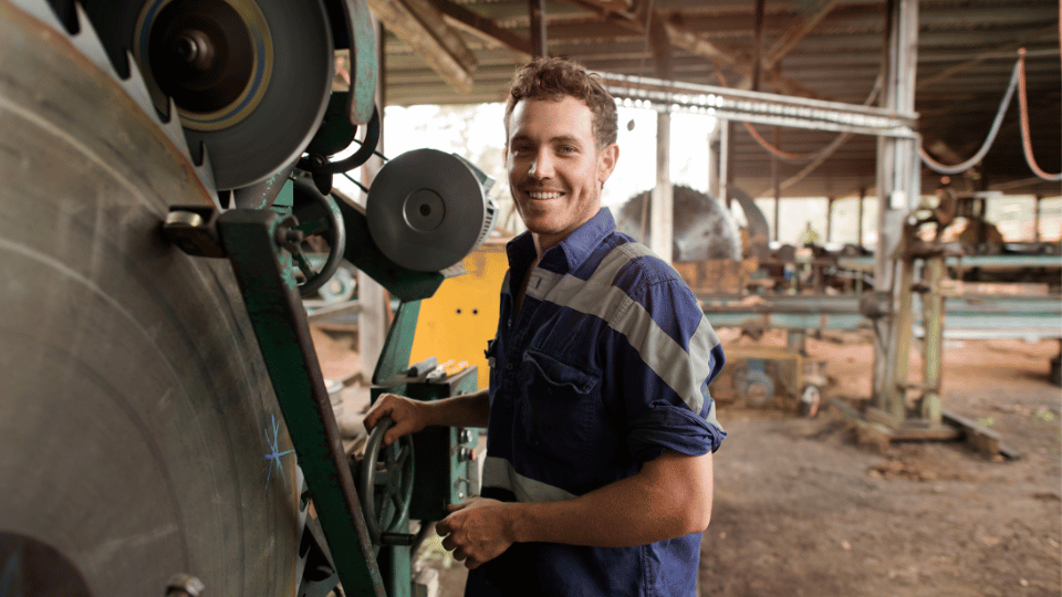 A smiling worker operates machinery in a workshop, illustrating how equipment financing can help businesses with bad credit secure essential tools and equipment.