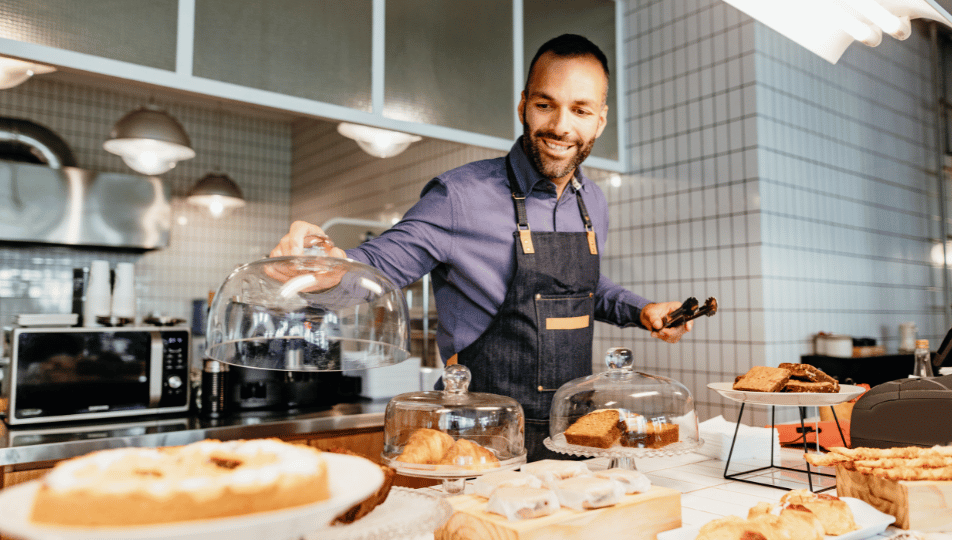 A smiling baker arranges pastries in a bakery, representing the growth potential with Hispanic business loans.