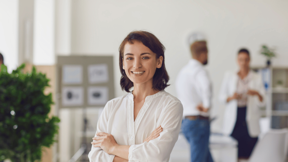 Mujer emprendedora sonriendo en una oficina, simbolizando preparación para aplicar a financiamiento de capital de trabajo.