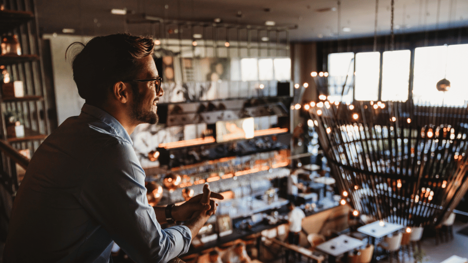 A business owner in a modern restaurant looking over the space, representing industries like hospitality and dining that are ideal for revenue-based financing.